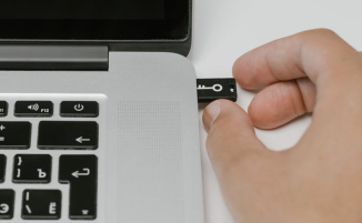 Hand steckt USB-Stick in Laptop